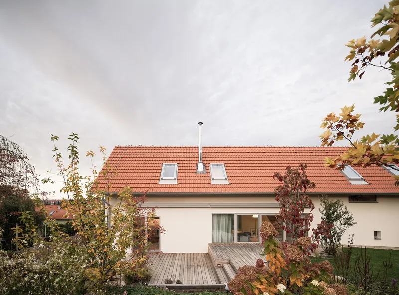 Garden view of the white stucco house with orange clay tile roof and timber deck in autumn