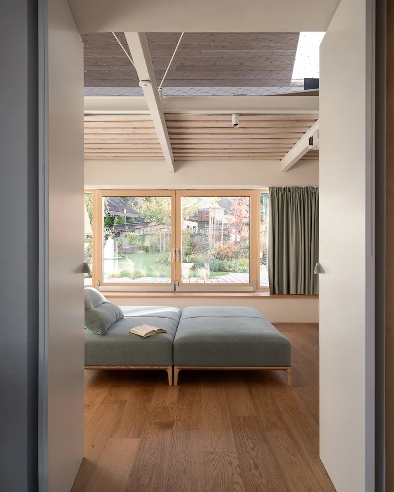 Living room with timber-framed glass doors opening to garden and exposed timber ceiling structure