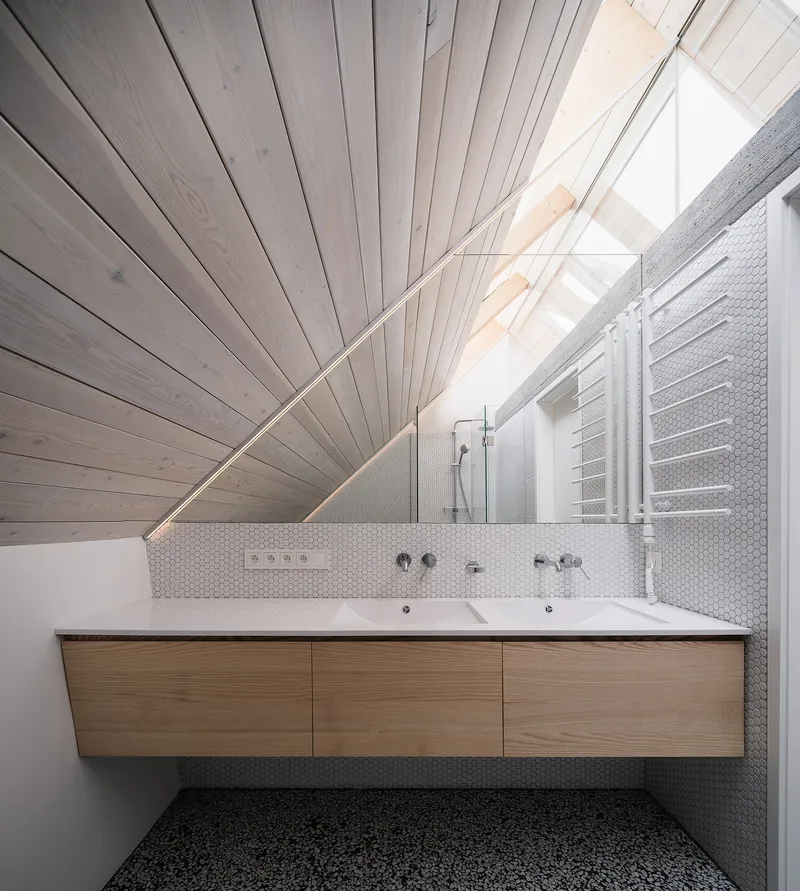 Bathroom with floating timber vanity beneath a white-painted timber ceiling sloping to a skylight