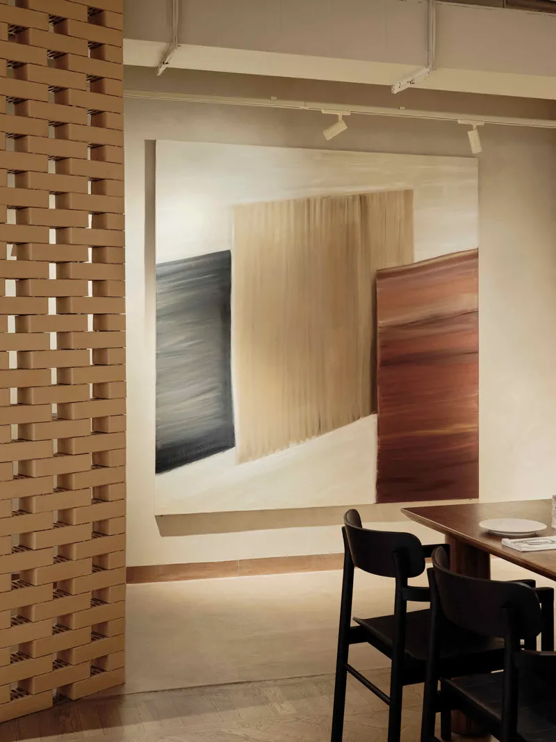 Doorway framed by a basketweave timber screen leading to a dining area with black chairs