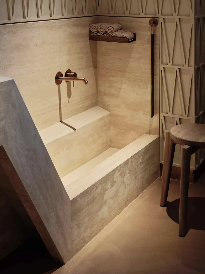 Concrete sink basin with bronze wall-mounted faucet and integrated stepped shelving