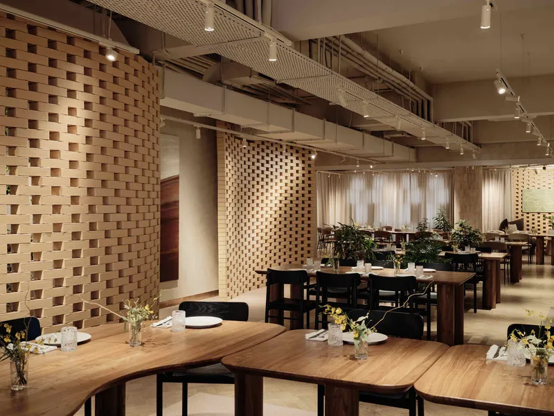 Dining space with perforated timber screens, exposed concrete ceiling beams, and track lighting overhead