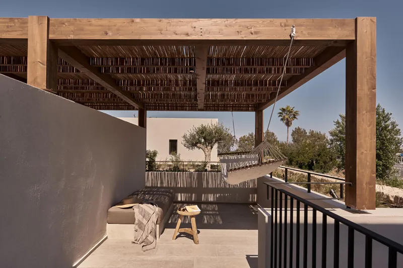 Rooftop terrace with timber pergola and woven reed screens overlooking olive trees and palms