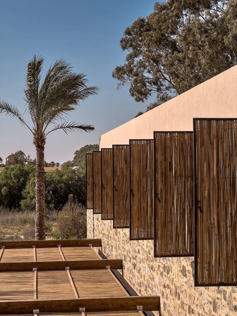 Stepped timber screens set in stone plinths ascending beside a timber deck walkway at dusk