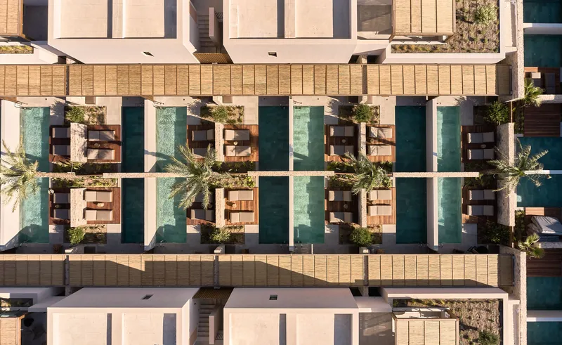 Drone view showing rows of private pools with timber pergolas and planted courtyards