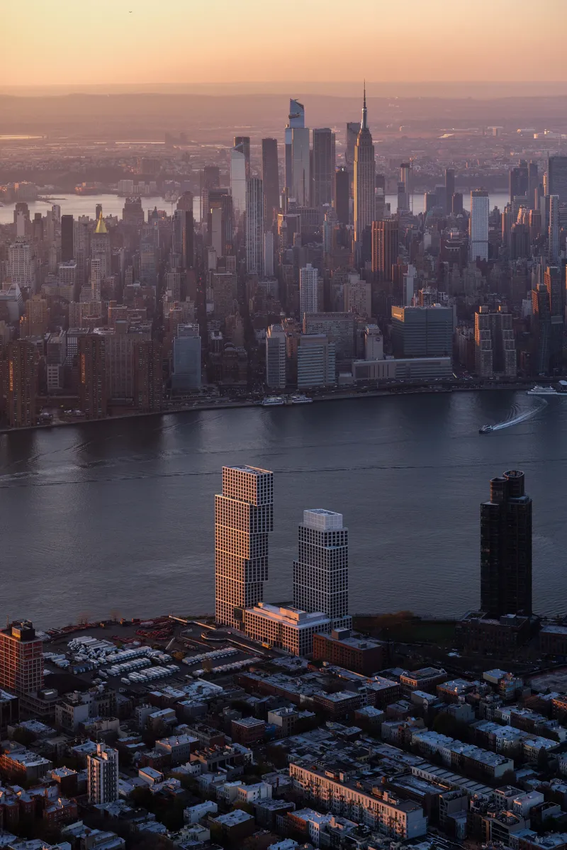 Aerial view of twin residential towers catching golden hour light above the waterfront skyline