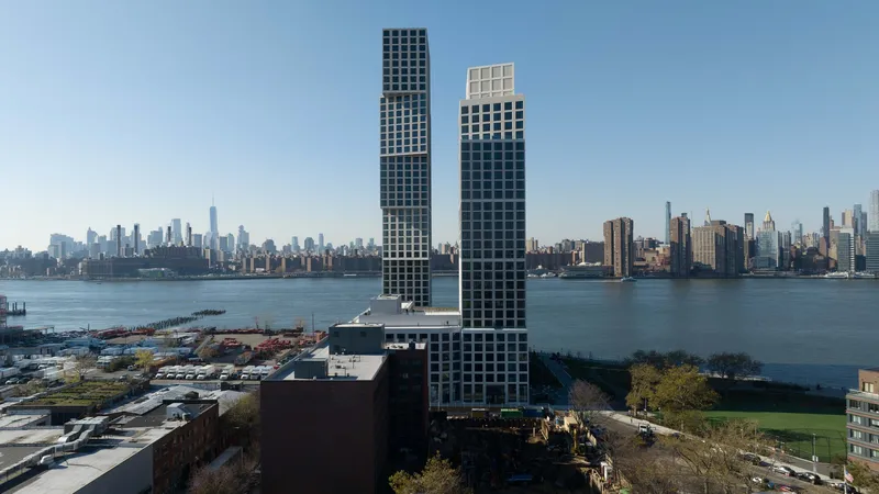 The twin towers rising from a waterfront site with harbor and distant cityscape beyond