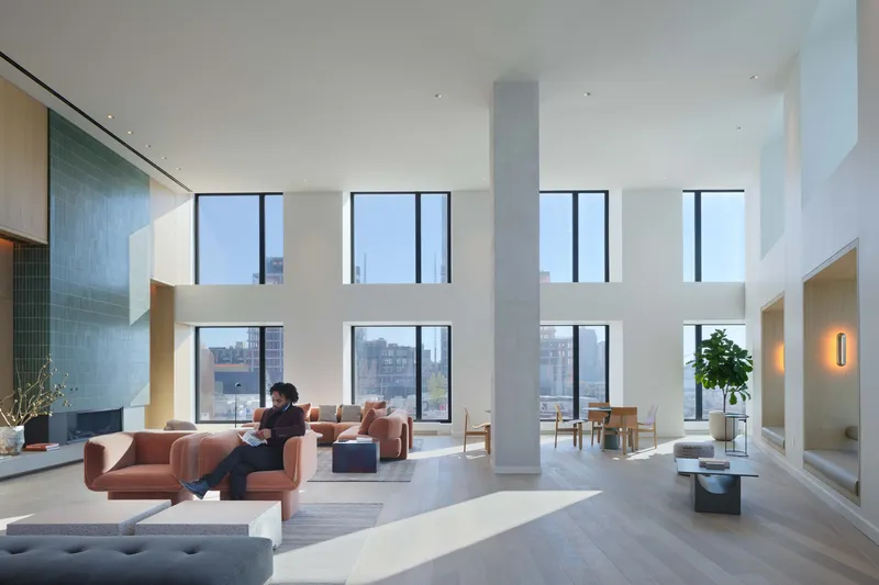 Double-height living room with floor-to-ceiling windows and a central structural column with a person seated