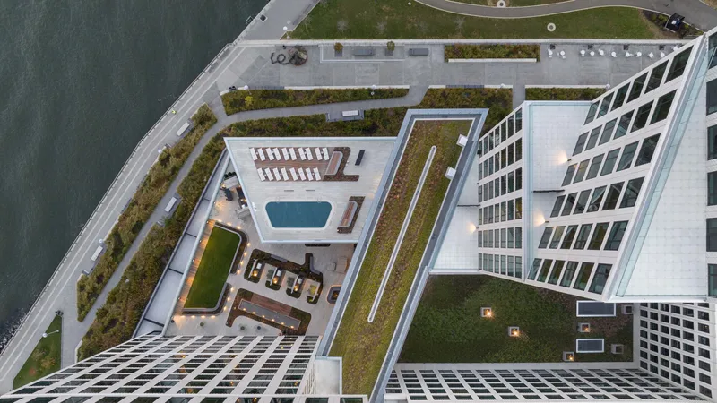 Aerial view of rooftop amenity terrace with swimming pool, green roof and waterfront promenade