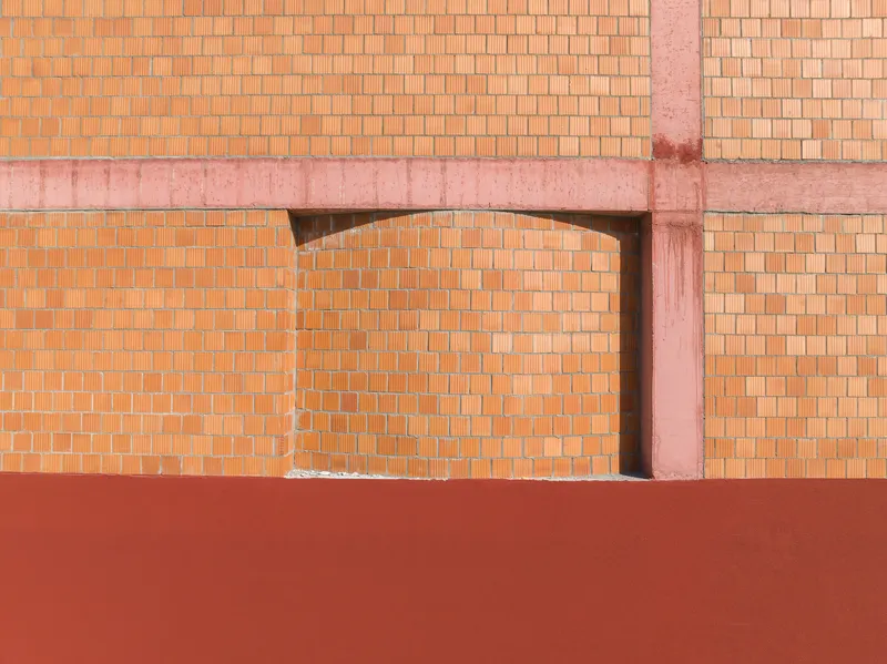 Detail of arched opening in terracotta brick wall with pink concrete structural frame