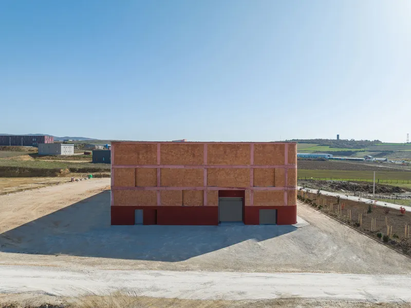 Rear elevation of the terracotta brick and red plaster facade on a gravel yard under clear sky