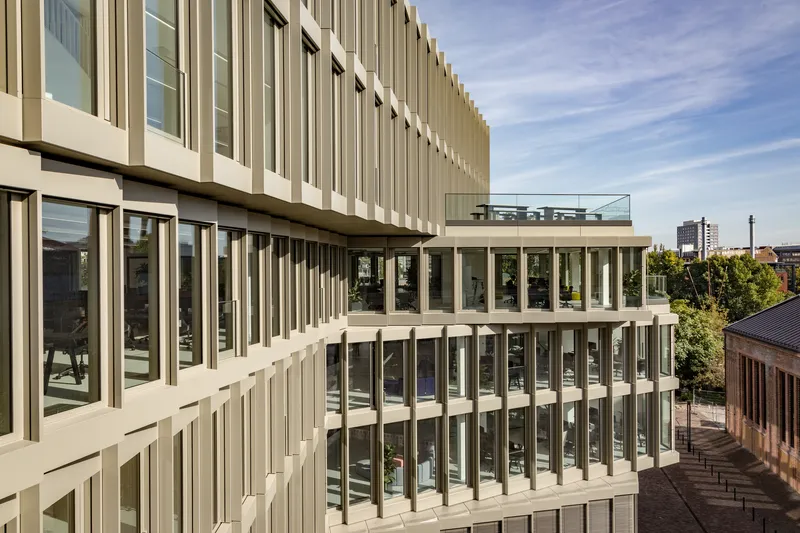 Angled view of stacked terraces with vertical white fins and floor-to-ceiling glazing in afternoon light