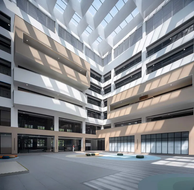 Interior courtyard atrium with diagonal skylights patterning sunlight across multi-story facades