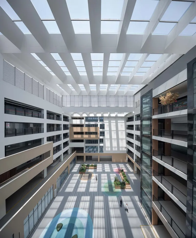 Interior courtyard with slatted skylight casting gridded shadows across multiple floor levels