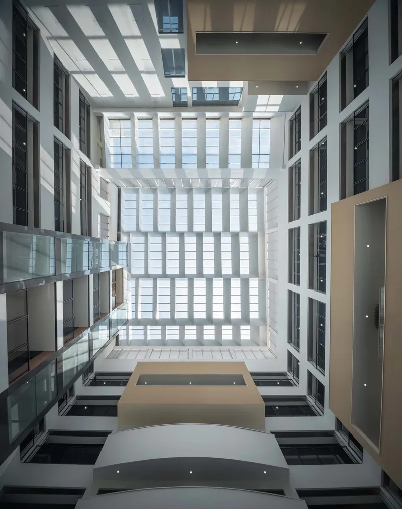 Upward view through the skylit atrium showing layered floor plates and horizontal louvers