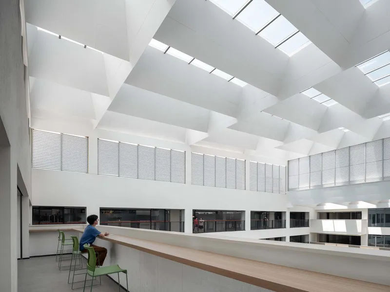 Interior atrium with coffered ceiling skylights and a person seated at a timber counter ledge