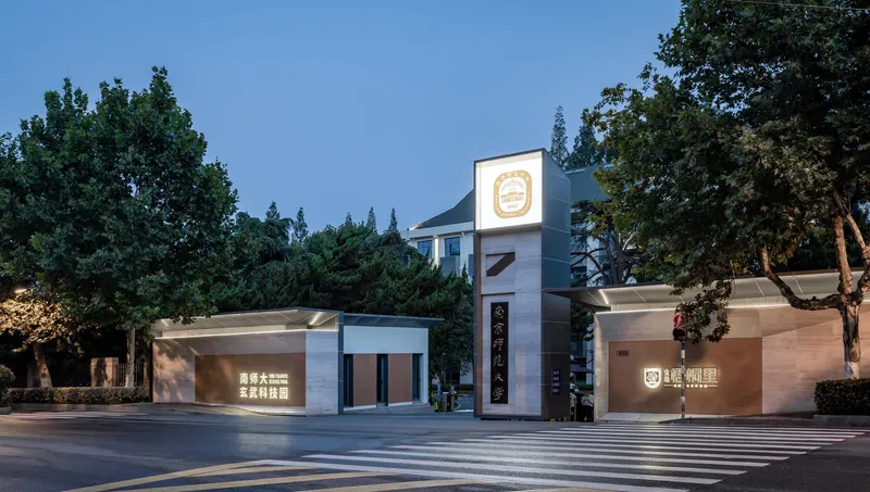 Street view of the entrance pavilion with vertical signage tower at twilight