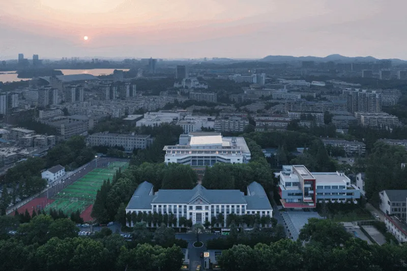 Aerial view of campus buildings and playing fields at sunset with distant mountains