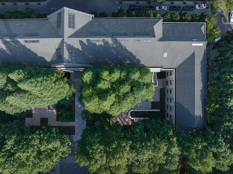 Drone view of the grey tiled roof with courtyard and tree canopies below
