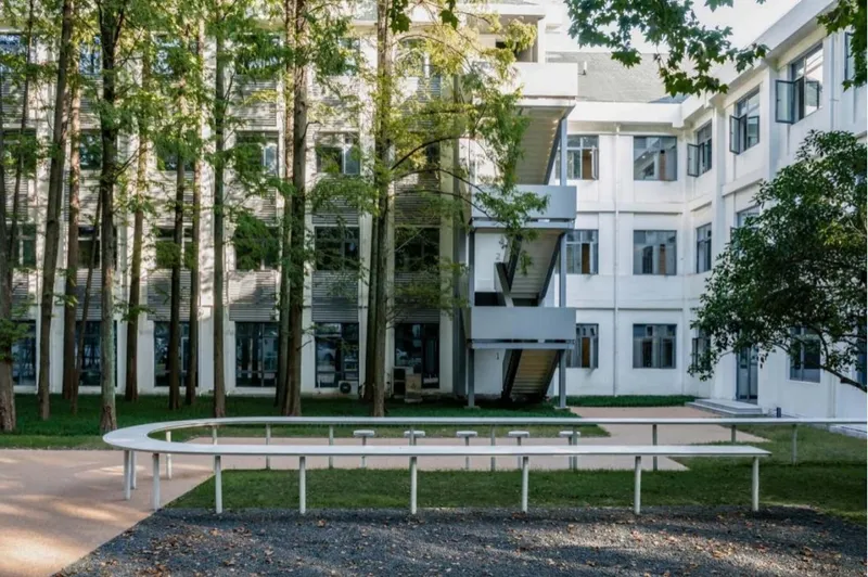 Circular white bench surrounding trees in a courtyard bordered by white facades