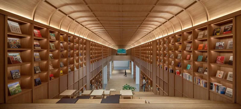 Two-story library interior with vaulted timber ceiling and illuminated book shelves lining the walls