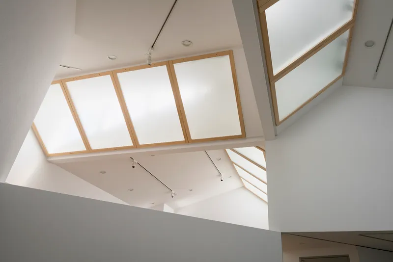 Upward view of timber-framed skylights and white walls in a multi-level interior volume