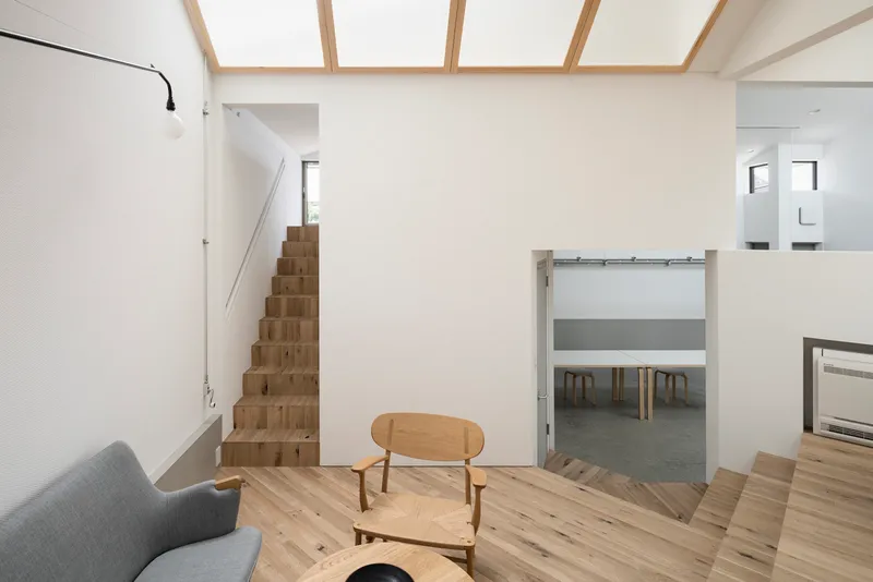 Living area with timber staircase and sliding door opening to a dining space below skylights