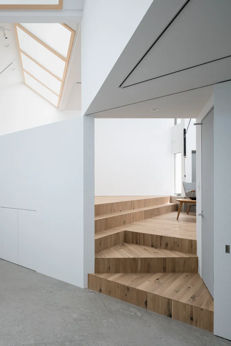 Timber stair treads rising from polished concrete floor toward an upper level living space