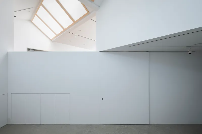 Minimalist white storage wall with polished concrete flooring and recessed ceiling panels