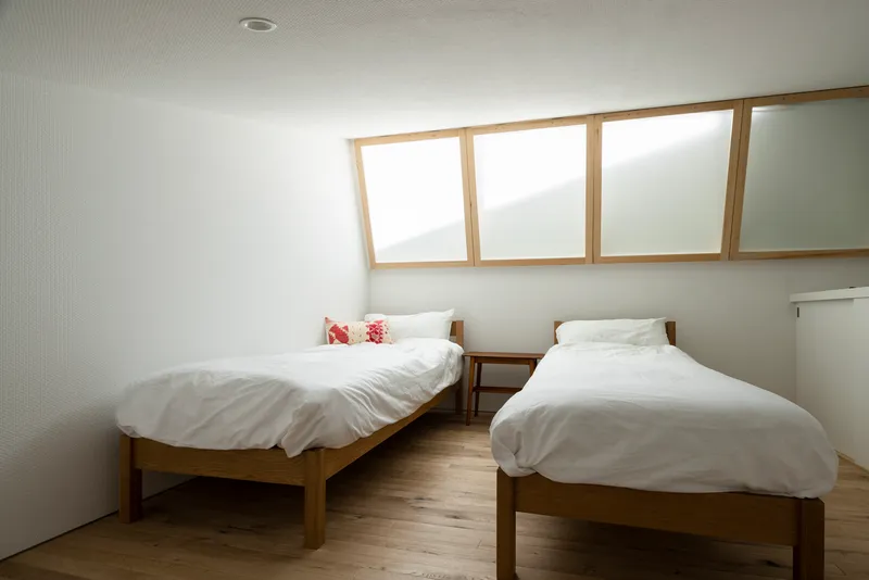 Bedroom with two timber beds beneath a ribbon of timber-framed clerestory windows
