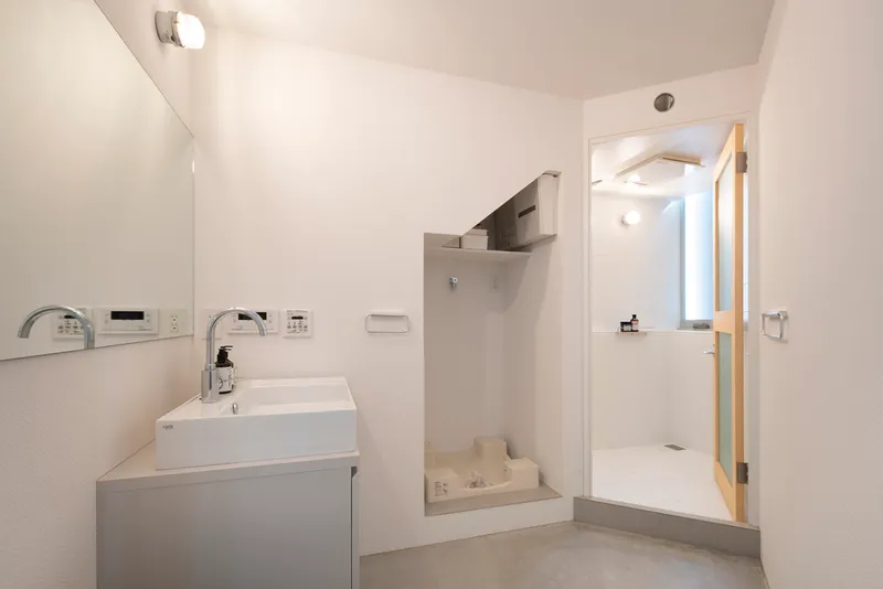 Bathroom with wall-mounted sink and open shower area separated by a low step