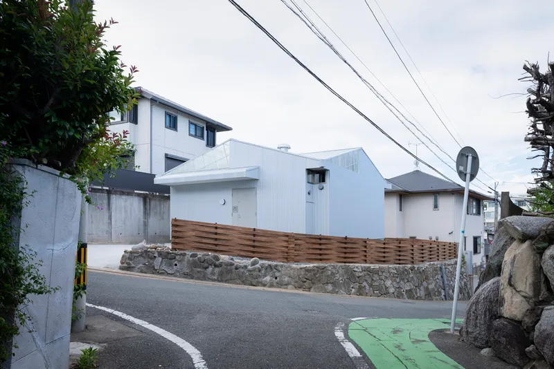 Street view with overhead power lines and timber fence screening the white corrugated metal structure
