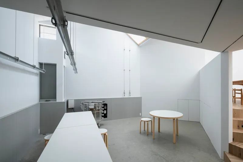 Kitchen and dining space with concrete floor and skylight above the white countertop and table