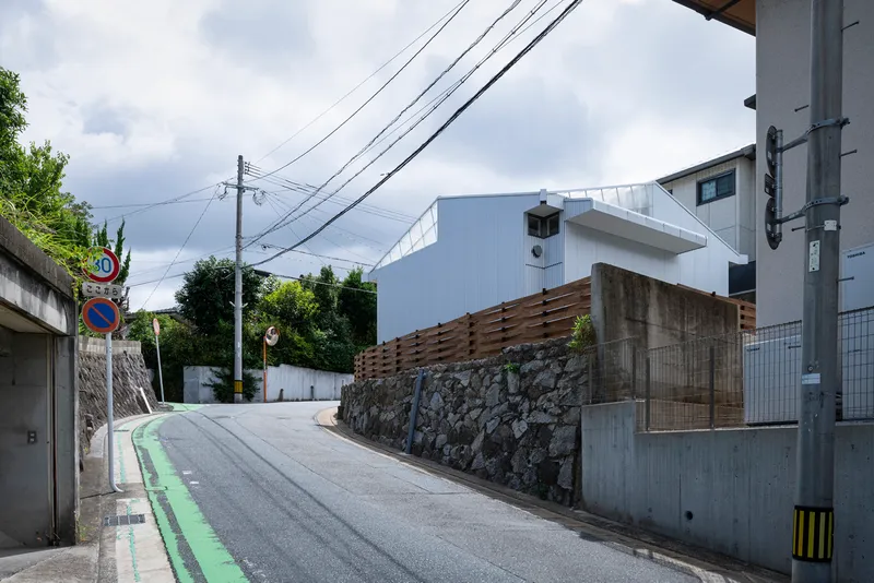 Sloping neighborhood street with the house set behind stone and timber boundary walls