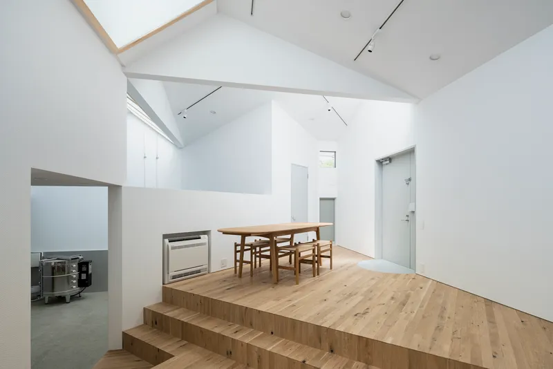 Raised timber platform with dining table and chairs beneath a vaulted ceiling with skylights