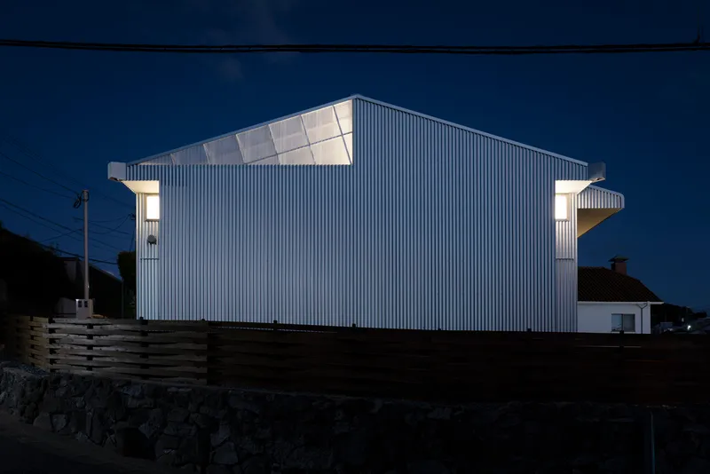 Rear elevation showing the angled roofline and projecting corner volumes at dusk