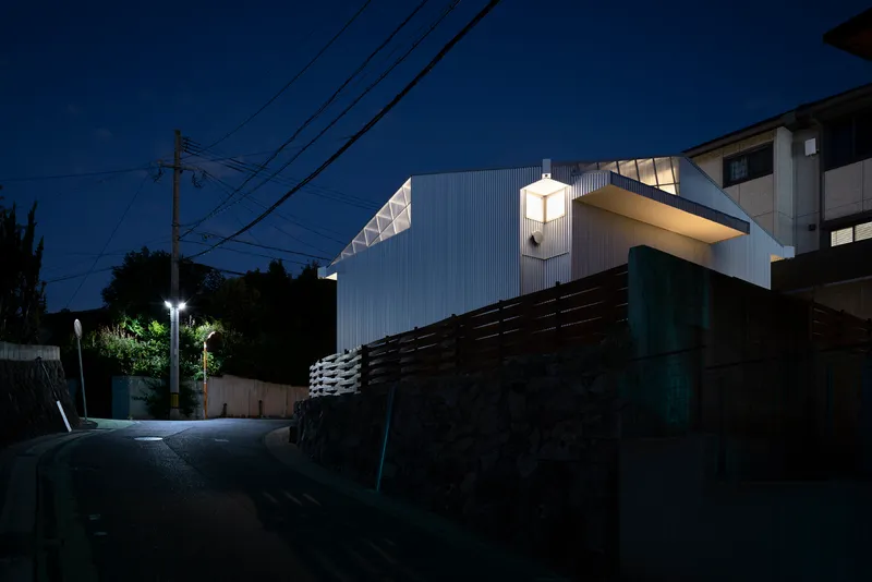 Uphill street approach with timber retaining wall and overhead power lines at night