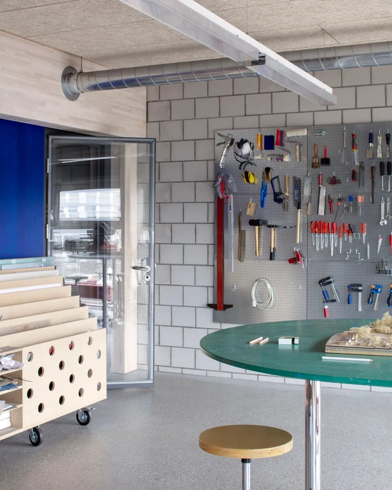 Workshop area with pegboard tool wall, round green work surface and concrete block partition