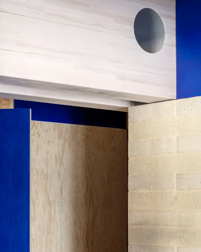 Doorway detail showing plywood door surrounded by blue panels and concrete block wall
