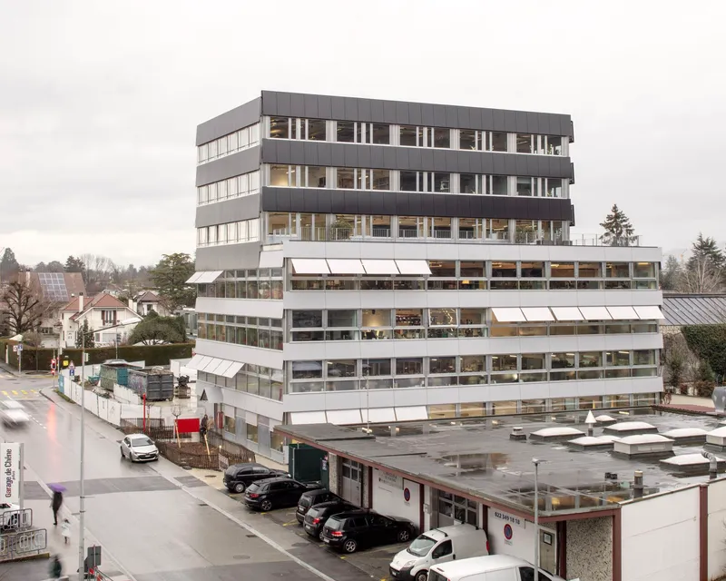Stacked office volumes with horizontal bands of windows and projecting awnings on an overcast day