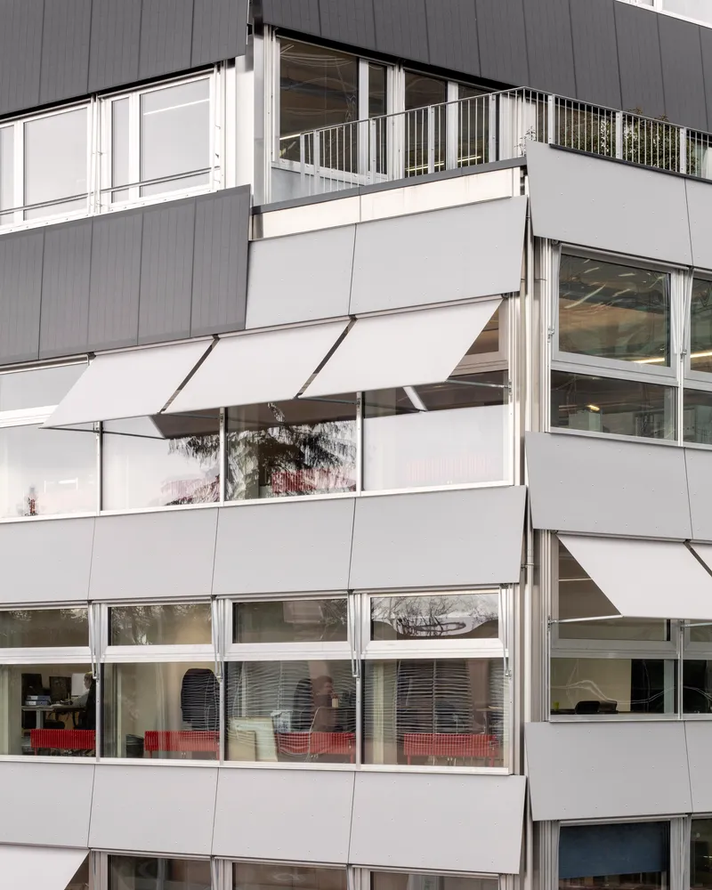 Facade detail showing staggered balconies with white awnings and horizontal window bands