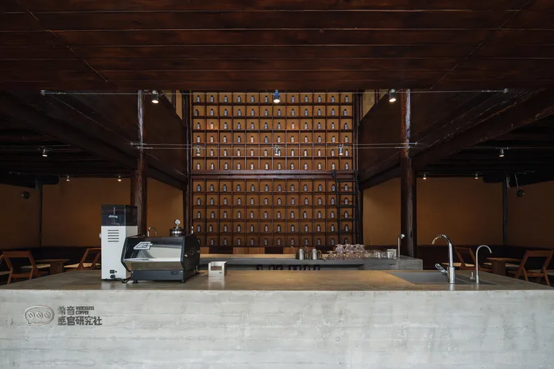 Service counter with grid of wooden storage drawers mounted on rear wall under dark timber ceiling