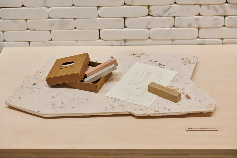Timber stamp and printed sheet displayed on a terrazzo slab beside an open box with tools