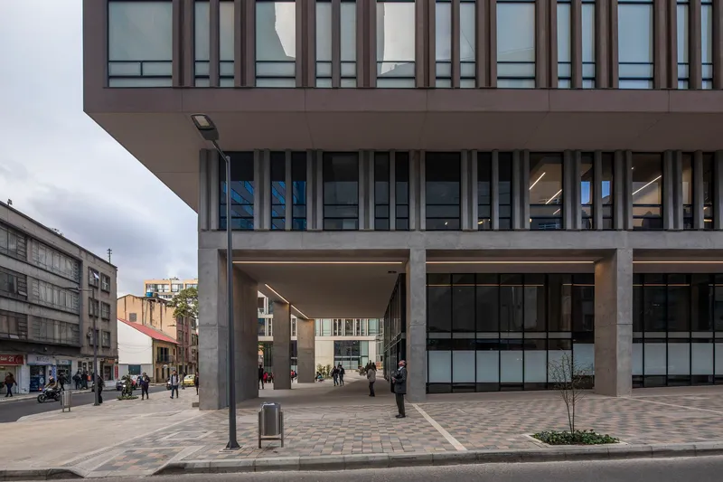 Street view of the raised concrete structure with a large passthrough opening to the plaza beyond