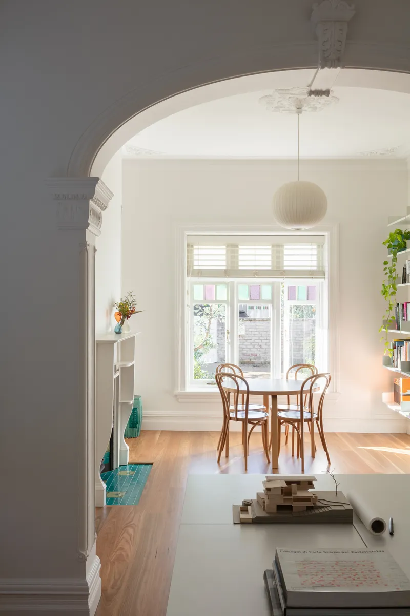 Dining room framed by an arched doorway with decorative corbels and pendant light overhead