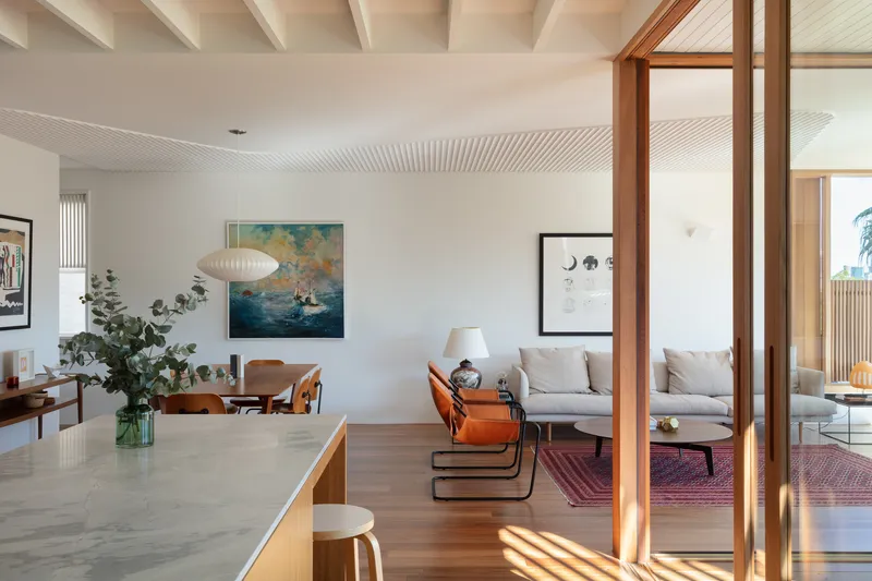 Open-plan living space with timber screen divider and exposed rafters in soft daylight