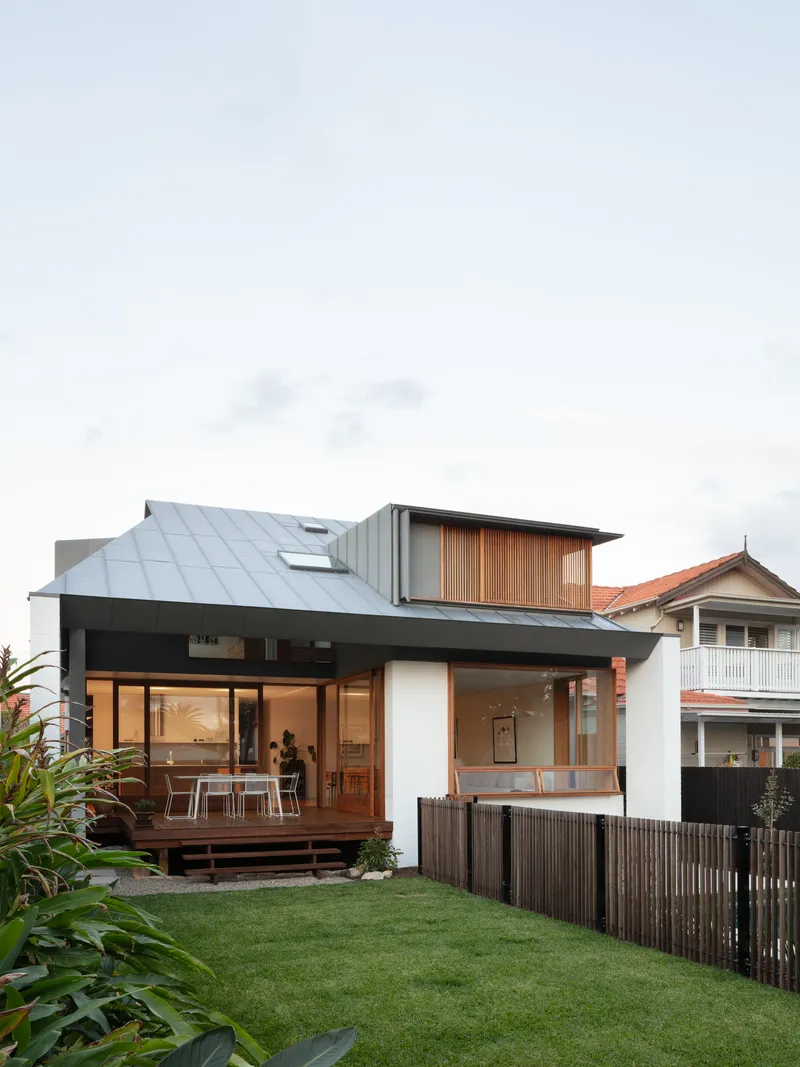 Street view showing sloped metal roof and timber upper volume above landscaped yard