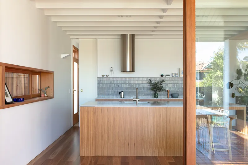 Kitchen island and pass-through niche with slatted screen looking toward exterior timber column and pool