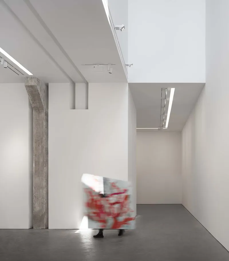 White gallery corner with mezzanine opening above and figure carrying painting in motion