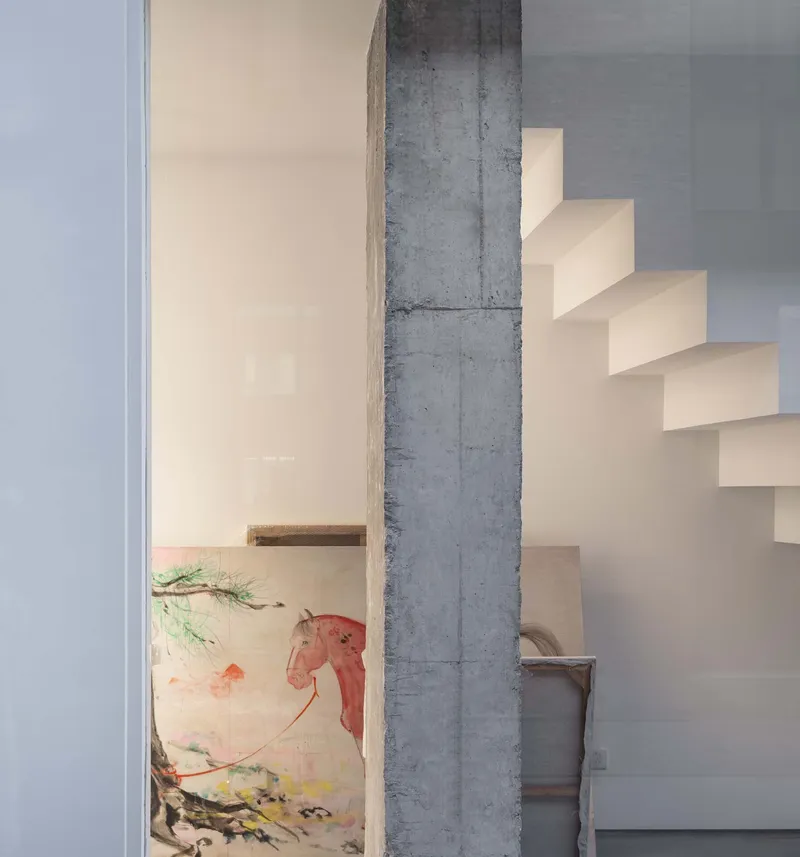 Concrete column beside a white folded staircase with a painting visible in the background